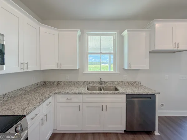 a kitchen with white cabinets and sink
