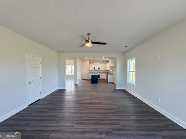 a view of an empty room with window and wooden floor