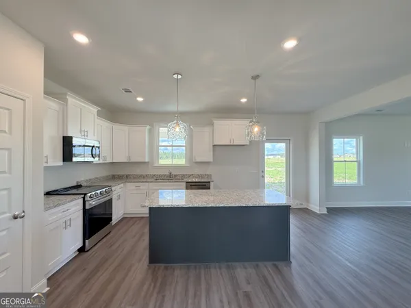 a large kitchen with stainless steel appliances lots of counter space and wooden floor