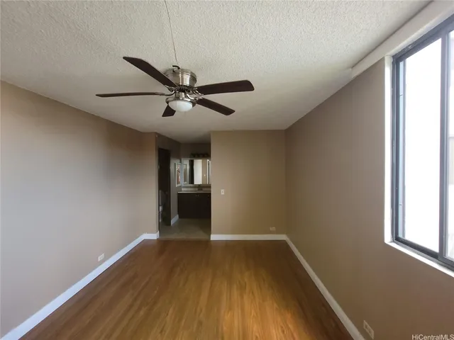 a view of empty room with wooden floor and fan