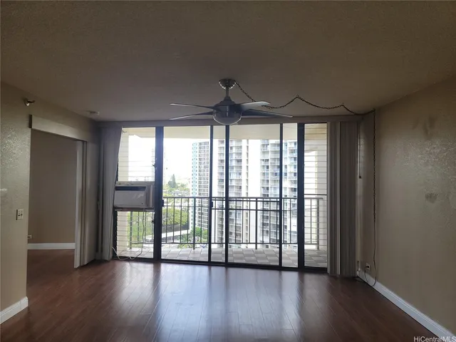 a view of an empty room with wooden floor and a window