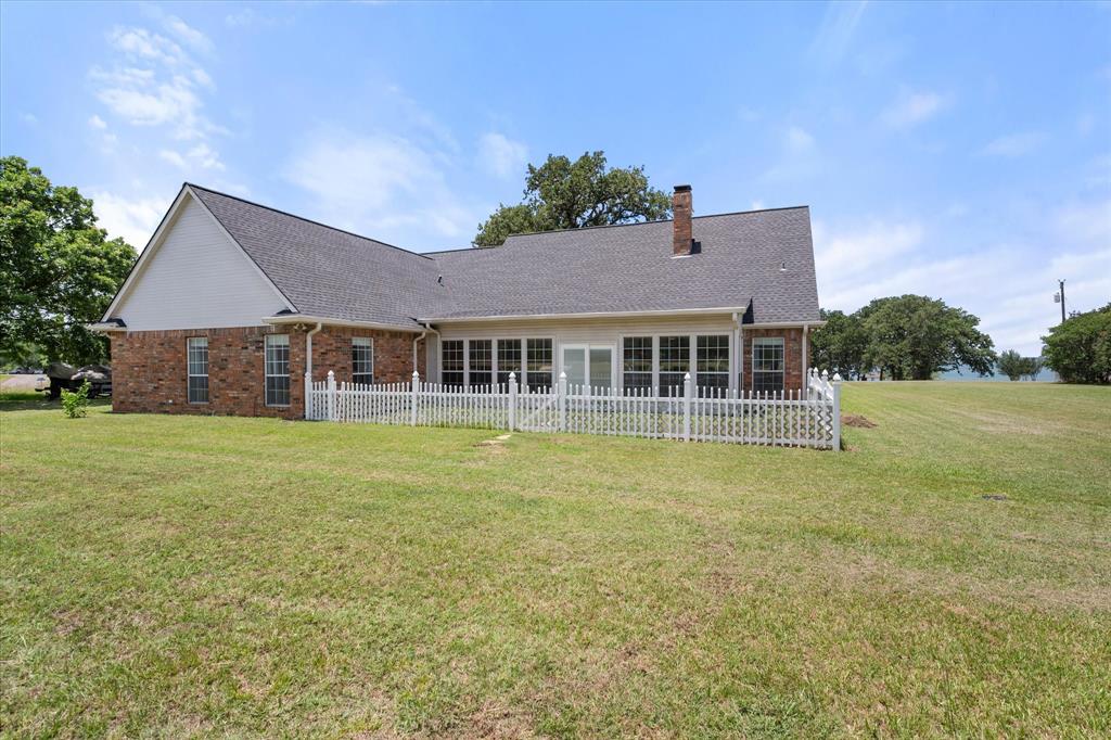 13021 Rudy's Way Streetman, TX 75859 - Photo 37 of 40 Rear exterior in Streetman, TX featuring brick construction, fenced patio area, and a spacious 1-acre yard.