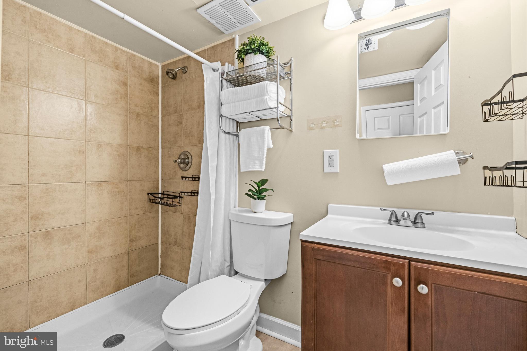 236 Inlet Drive Pasadena, MD 21122 - Photo 21 of 33 a bathroom with a sink a toilet a mirror and shower