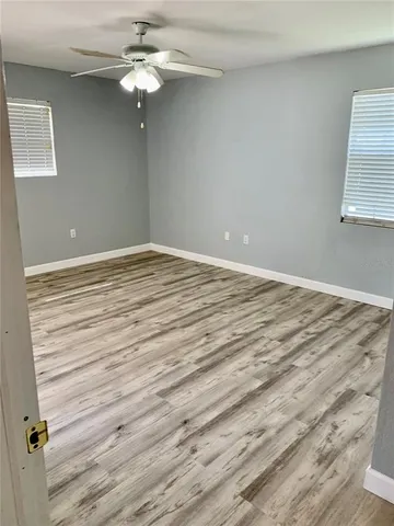 a view of an empty room with wooden floor and a window