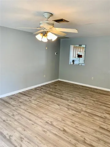 a view of a room with wooden floor and ceiling fan