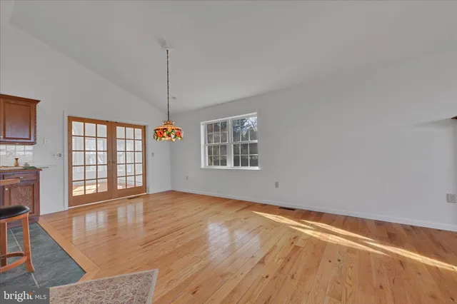 a view of an empty room with window and wooden floor