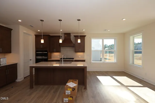 a kitchen with kitchen island granite countertop a stove a sink a refrigerator and a dining table with wooden floor