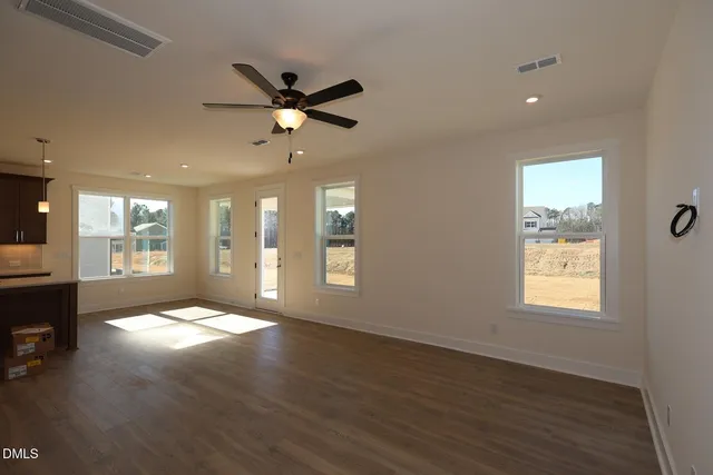 a view of an empty room with window and wooden floor
