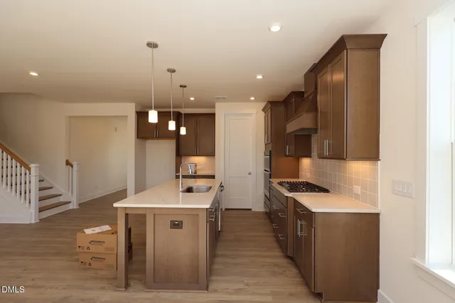 a kitchen with stainless steel appliances kitchen island granite countertop a stove a sink and a refrigerator