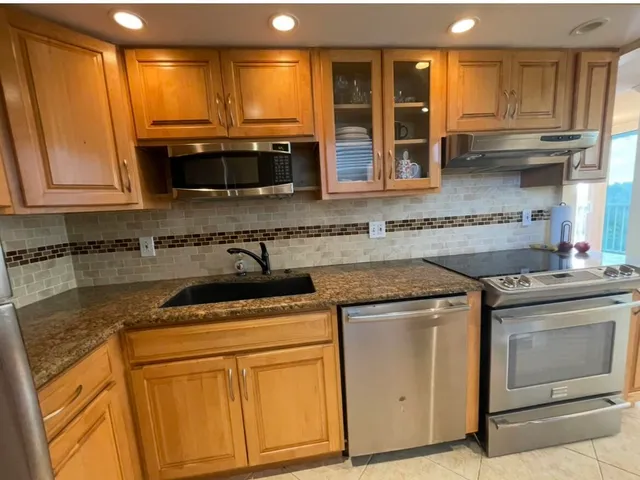 a kitchen with stainless steel appliances granite countertop a stove a sink and a microwave