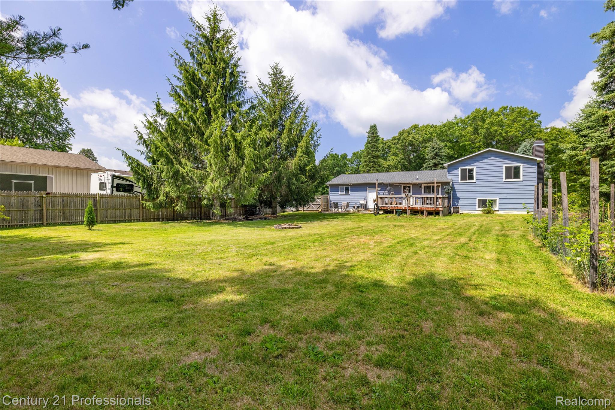 15037 Hogan Road Linden, MI 48451 - Photo 33 of 38 Expansive lawn area with a blue-sided exterior and a rear deck