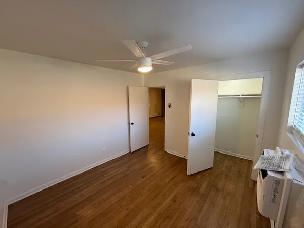 an empty room with wooden floor and a ceiling fan