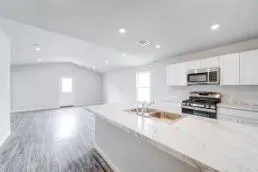 a kitchen with stainless steel appliances a stove a sink a refrigerator white cabinets and wooden floor