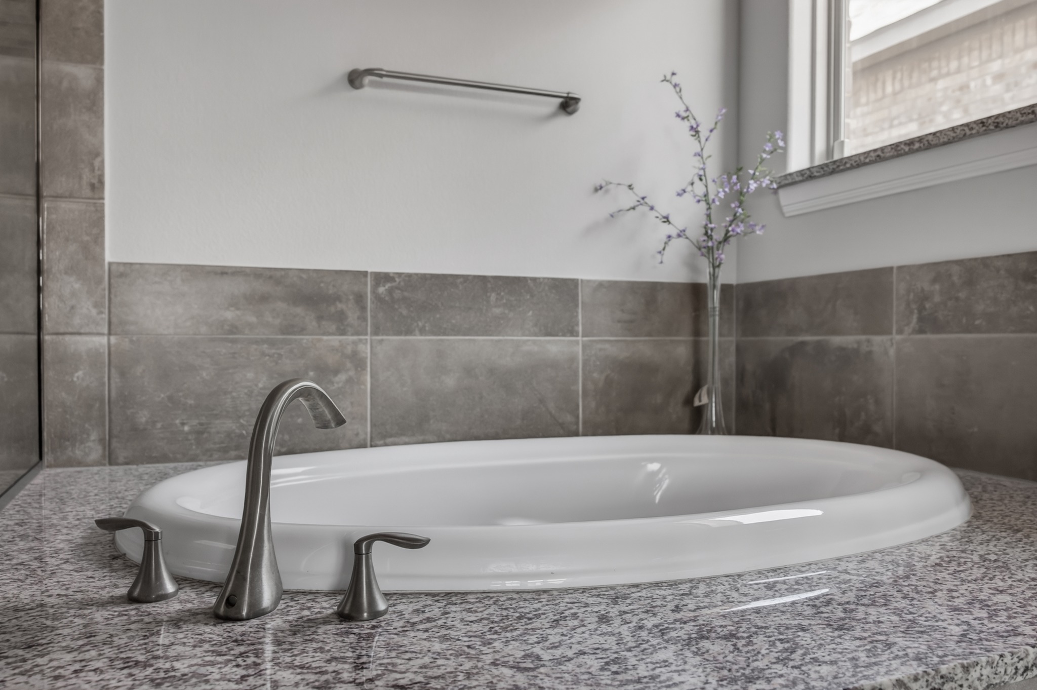 4105 Haight Street Round Rock, TX 78681 - Photo 23 of 40 Integral soaking tub with a brushed nickel faucet set, surrounded by a speckled granite countertop