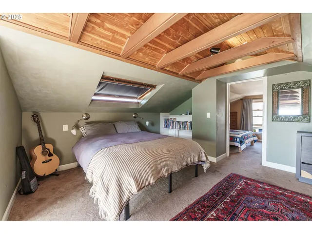 a bedroom with a bed a flat tv screen and a dresser