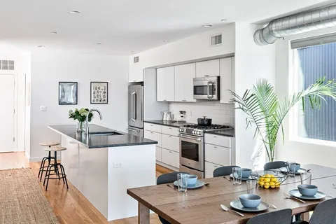 a kitchen with a refrigerator a stove a sink dishwasher and white cabinets with wooden floor