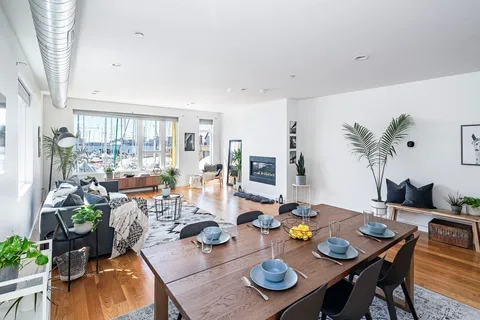 a view of a dining room with furniture a potted plant and wooden floor