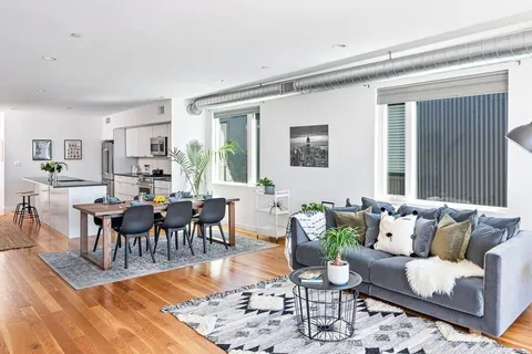 a living room with furniture wooden floor and a dining table