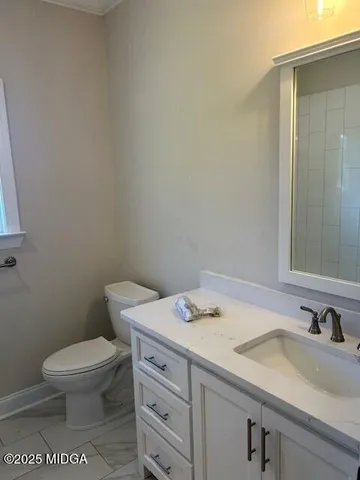 a bathroom with a granite countertop toilet sink and mirror