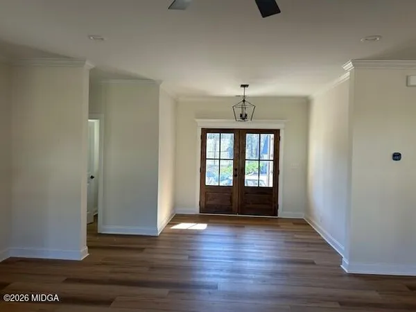 a view of an empty room with wooden floor and a window