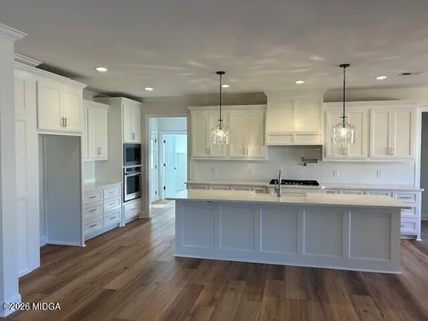 a large kitchen with stainless steel appliances refrigerator a stove and wooden floors