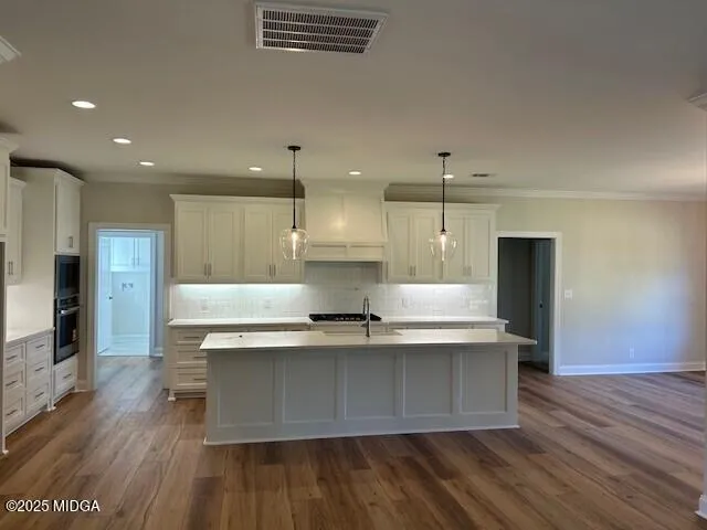 a view of kitchen with kitchen island a sink wooden floor and stainless steel appliances