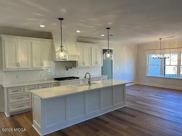 a kitchen with stainless steel appliances granite countertop a sink a stove and a wooden floors