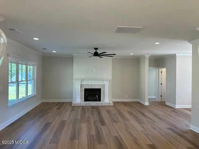 an empty room with wooden floor fireplace and windows