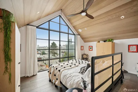 a bedroom with a bed and a large window with the outer view