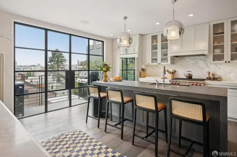 a kitchen with stainless steel appliances granite countertop a stove top oven a sink a dining table and chairs with wooden floor