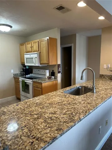 a kitchen with granite countertop a stove top oven and cabinets