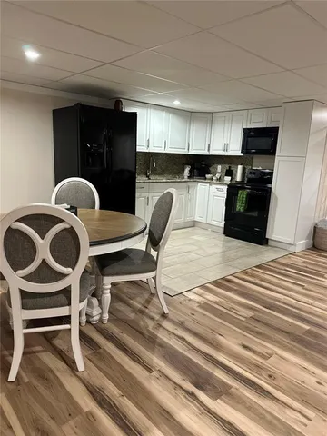 a kitchen with a table chairs a refrigerator and cabinets