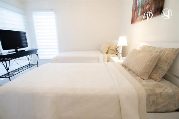 a spacious bedroom with a bed and a flat screen tv