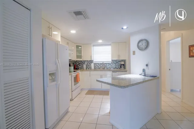 a kitchen with stainless steel appliances granite countertop a sink and a refrigerator
