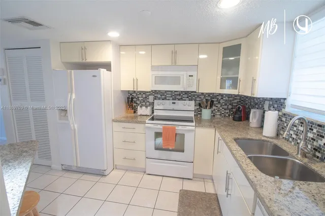 a kitchen with stainless steel appliances granite countertop a sink and a refrigerator