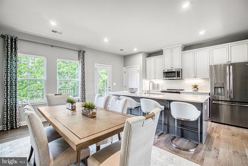 19756 Canopy Loop, Unit 328D Montgomery Village, MD 20886 - Photo 9 of 27 a kitchen with a table chairs microwave and refrigerator