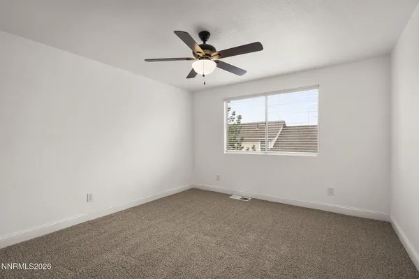 an empty room with a window and a ceiling fan