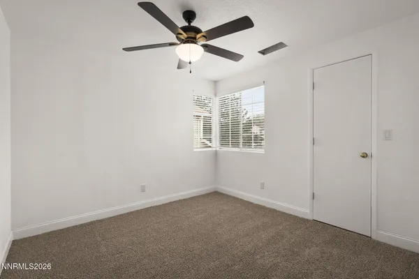an empty room with windows and fan