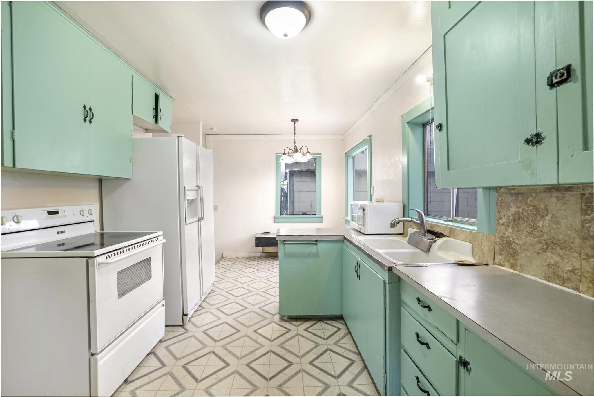 250 Elm Street Twin Falls, ID 83301 - Photo 13 of 28 Kitchen with white appliances, green cabinetry, crown molding, and hanging light fixtures