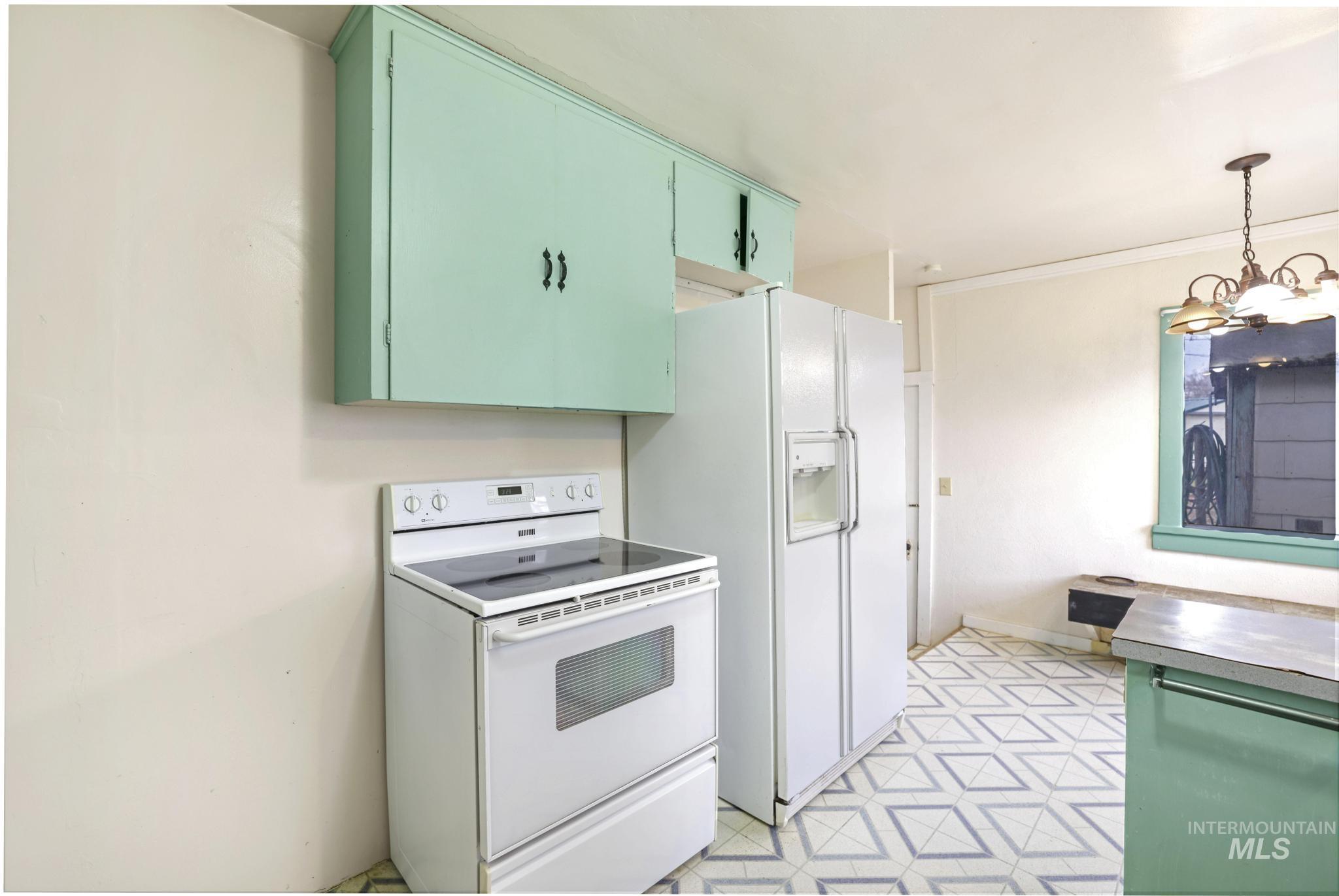 250 Elm Street Twin Falls, ID 83301 - Photo 14 of 28 Kitchen with white electric range, green cabinets, decorative light fixtures, light flooring, and a chandelier