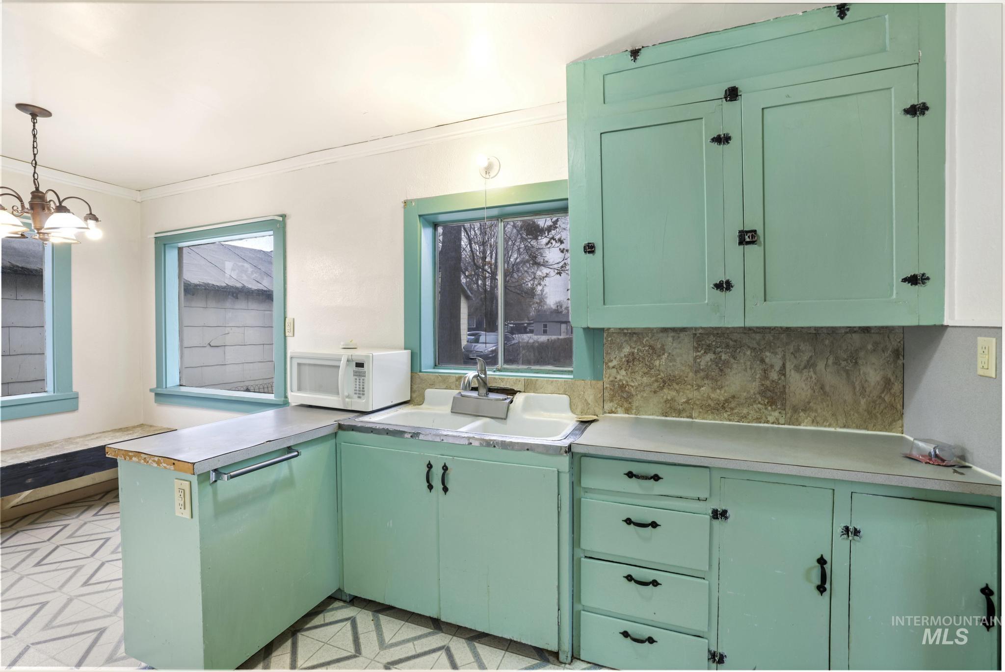 250 Elm Street Twin Falls, ID 83301 - Photo 15 of 28 Kitchen featuring green cabinetry, light countertops, a peninsula, white microwave, and crown molding