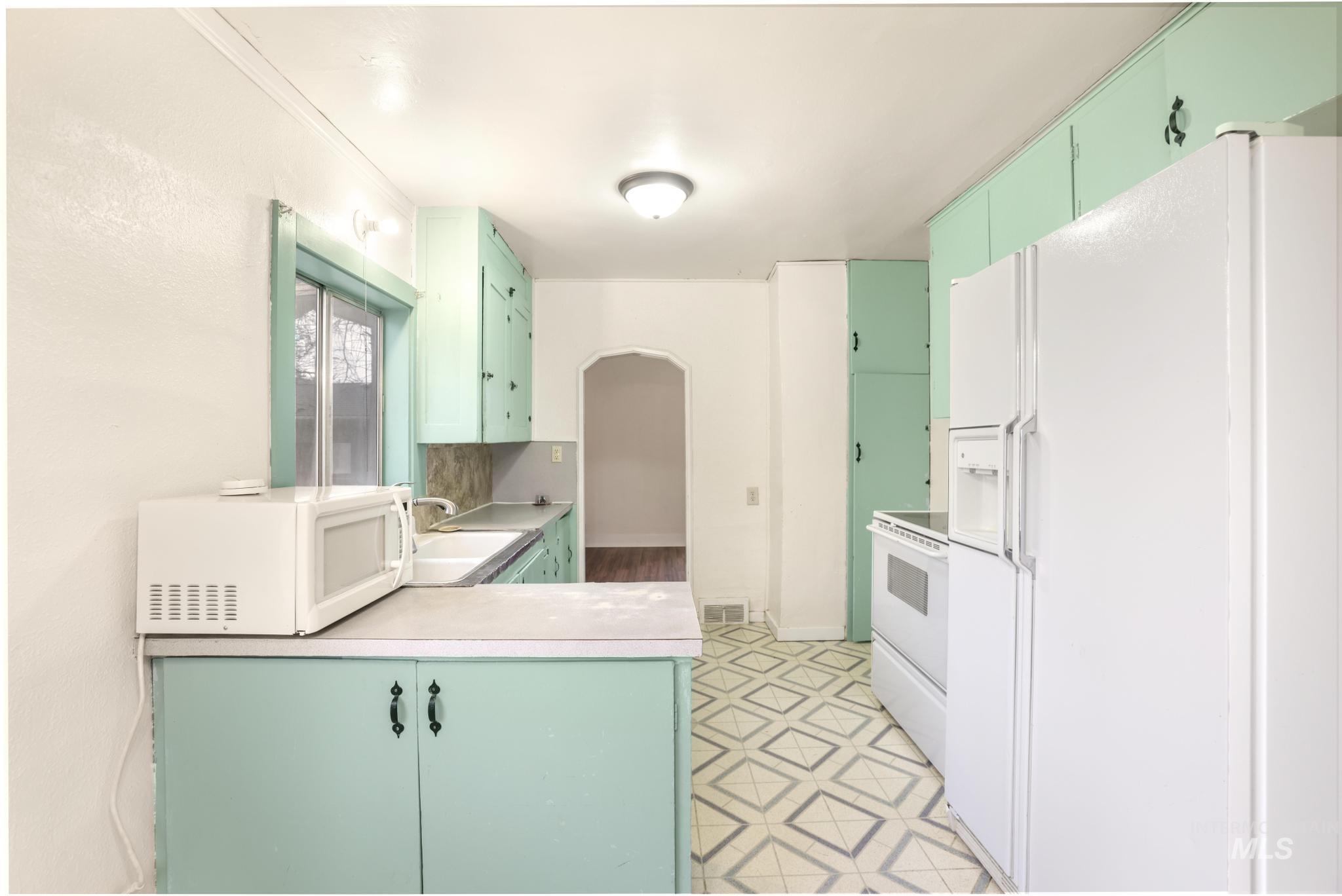 250 Elm Street Twin Falls, ID 83301 - Photo 16 of 28 Kitchen with white appliances, green cabinetry, light countertops, arched walkways, and a peninsula