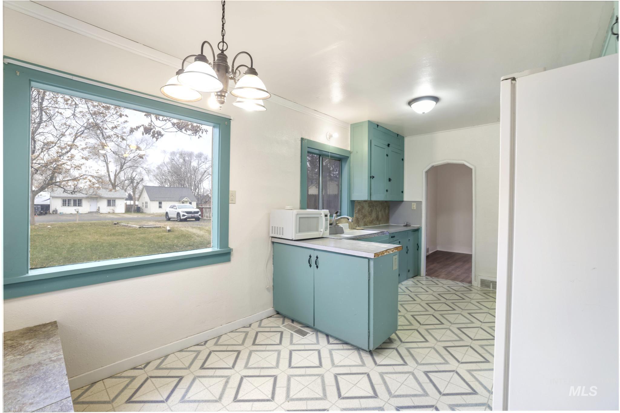 250 Elm Street Twin Falls, ID 83301 - Photo 17 of 28 Kitchen with white appliances, ornamental molding, decorative light fixtures, light countertops, and arched walkways