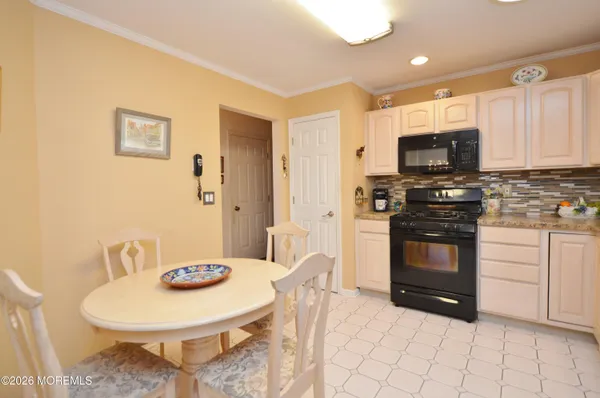 a kitchen with stainless steel appliances kitchen island granite countertop a refrigerator a stove a microwave oven with white cabinets and wooden floor