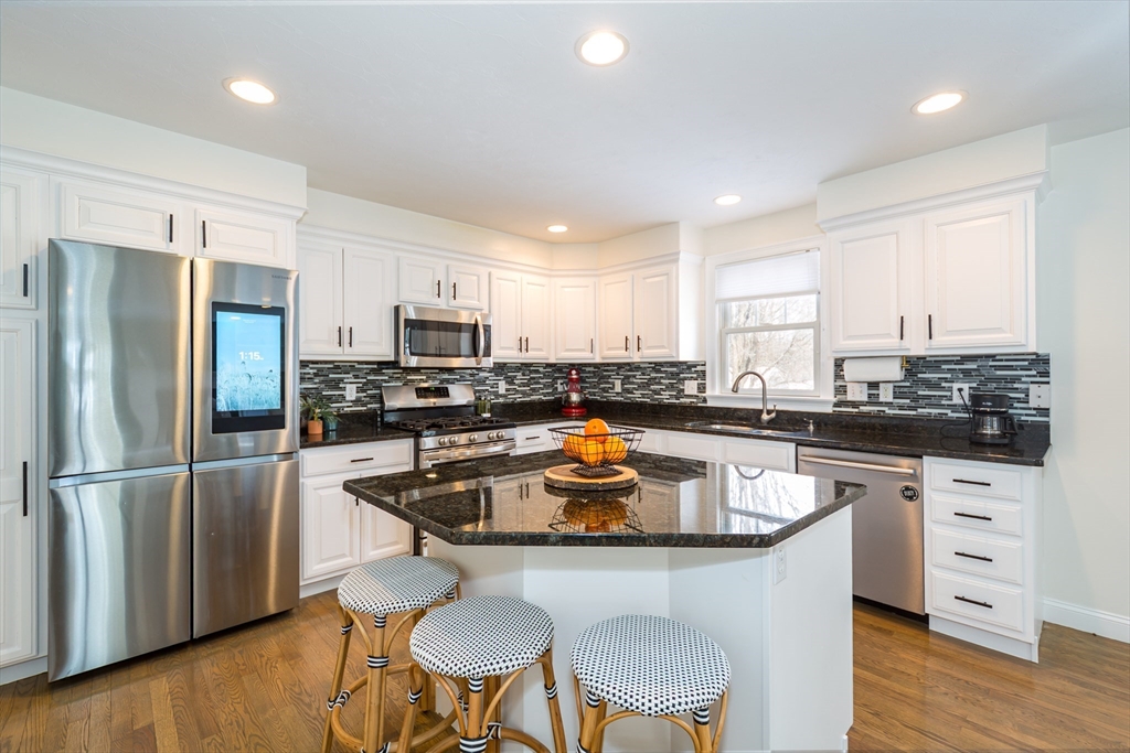 26 Wellesley Avenue, Unit B Natick, MA 01760 - Photo 11 of 34 a kitchen with stainless steel appliances granite countertop a stove a sink a microwave a refrigerator white cabinets and wooden floor