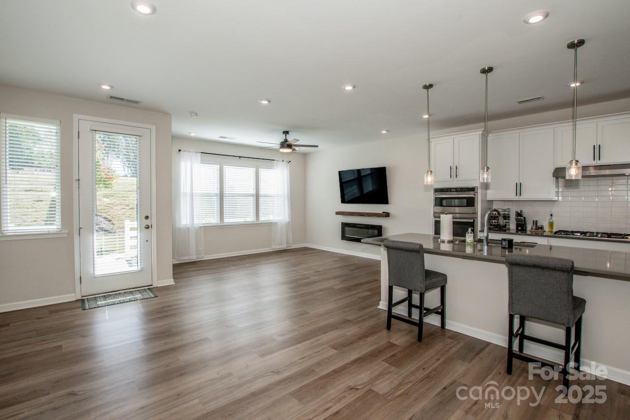 1270 Brawley School Road, Unit F Mooresville, NC 28117 - Photo 11 of 47 a kitchen with stainless steel appliances granite countertop a stove top oven a sink a dining table and chairs with wooden floor