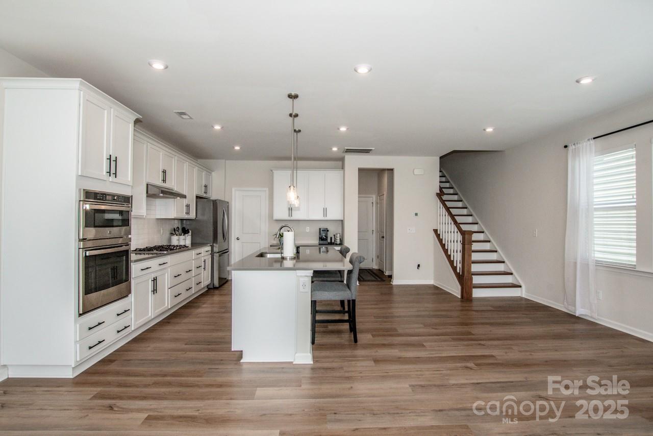 1270 Brawley School Road, Unit F Mooresville, NC 28117 - Photo 10 of 47 a kitchen with stainless steel appliances kitchen island granite countertop a stove top oven a sink a dining table and chairs