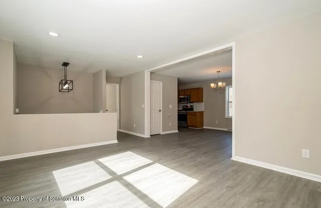 an empty room with kitchen view and windows