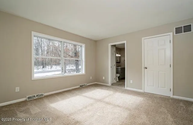 a view of an empty room with window and closet area