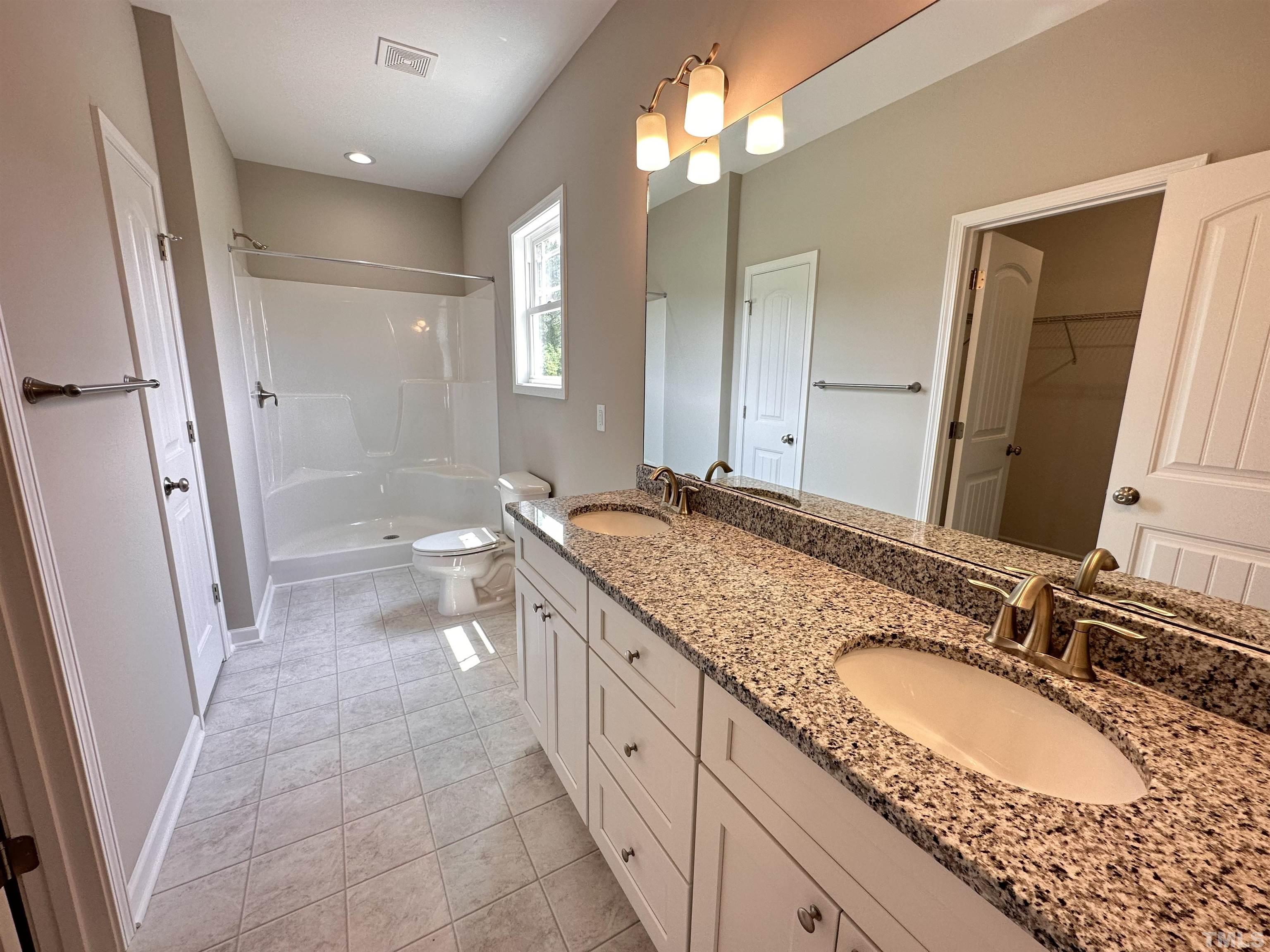 7517 Springfield School Road Lucama, NC 27851 - Photo 8 of 8 a spacious bathroom with a granite countertop double vanity sink a mirror and a shower